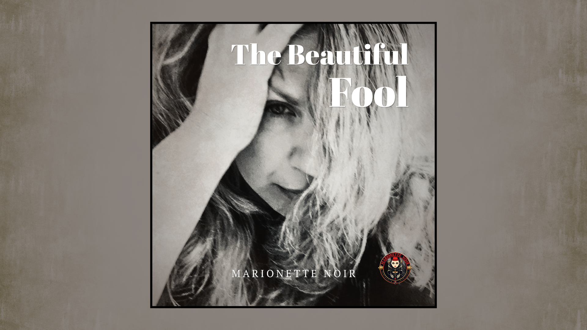 Official cinematic black-and-white cover art for 'The Beautiful Fool' by Melodic Noir artist Marionette Noir, featuring a high-contrast portrait, stark white typography for the title, and the project's signature red-and-black logo.